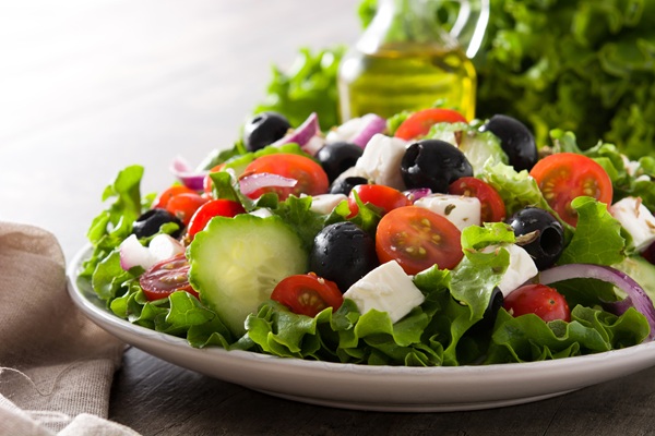Fresh Greek salad in bowl with black olive,tomato,feta cheese, cucumber and onion on wooden table.