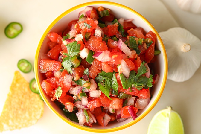 Bowl of tasty Pico de Gallo salsa and nachos on table