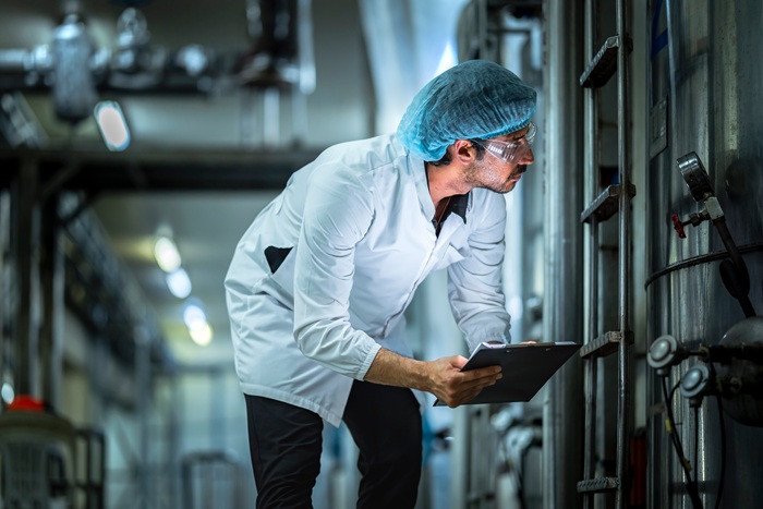 Technician examining industrial machinery in a food manufacturing environment