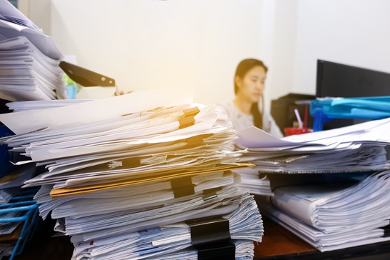 Many documents on the employee's desk with selective focus