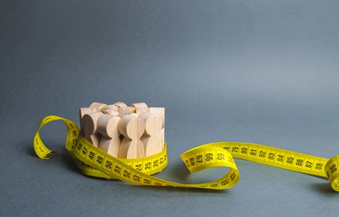 A crowd of wooden figures Gripped by measuring tape. Information statistics, measurement of the number, trends of population growth. Social Sciences. Promotion of ideas for weight loss, lifestyle